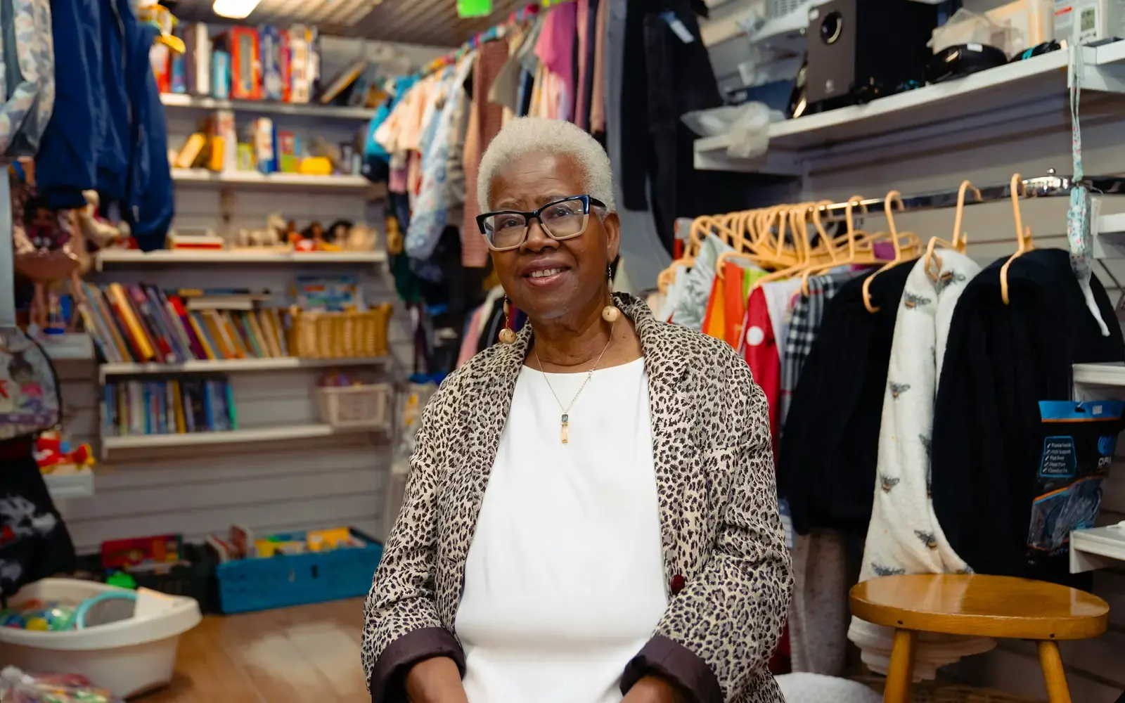 A shopkeeper smiling among racks of clothes in her shop