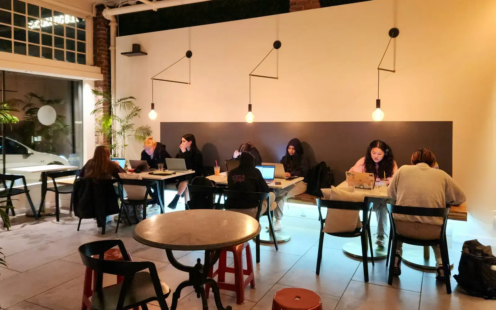 People working at small tables in a bright cafe